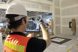 A crew member uses a ruggedized tablet equipped with augmented reality software to visualize the BIM geometry of a complex stai A crew member uses a ruggedized tablet equipped with augmented reality software to visualize the BIM geometry of a complex stai