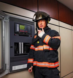 A firefighter uses the voice capabilities of a fire alarm panel (in this case, a A firefighter uses the voice capabilities of a fire alarm panel (in this case, a