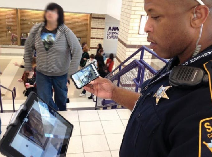 Collin County Sheriff Deputy George White checks a hallway in one of Anna (Texas) ISDs buildings while monitoring two others on