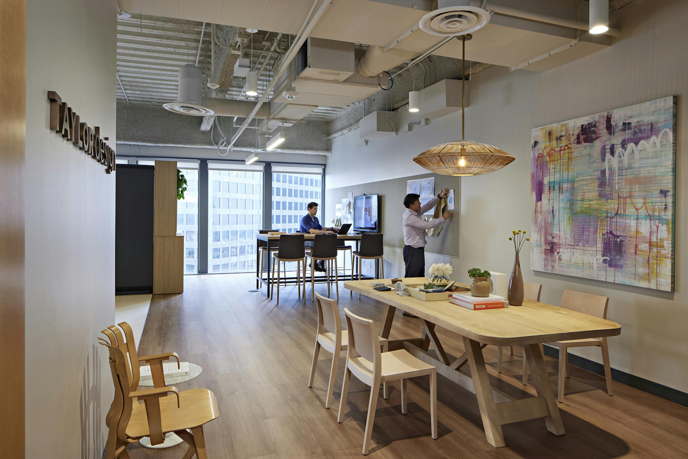 This Photo Of Taylor Design&rsquo;s La Office Shows Standard Branding, Decorative Lighting, And A Family Table (the 70%), With Community Art (the 30%) Unique To The Location