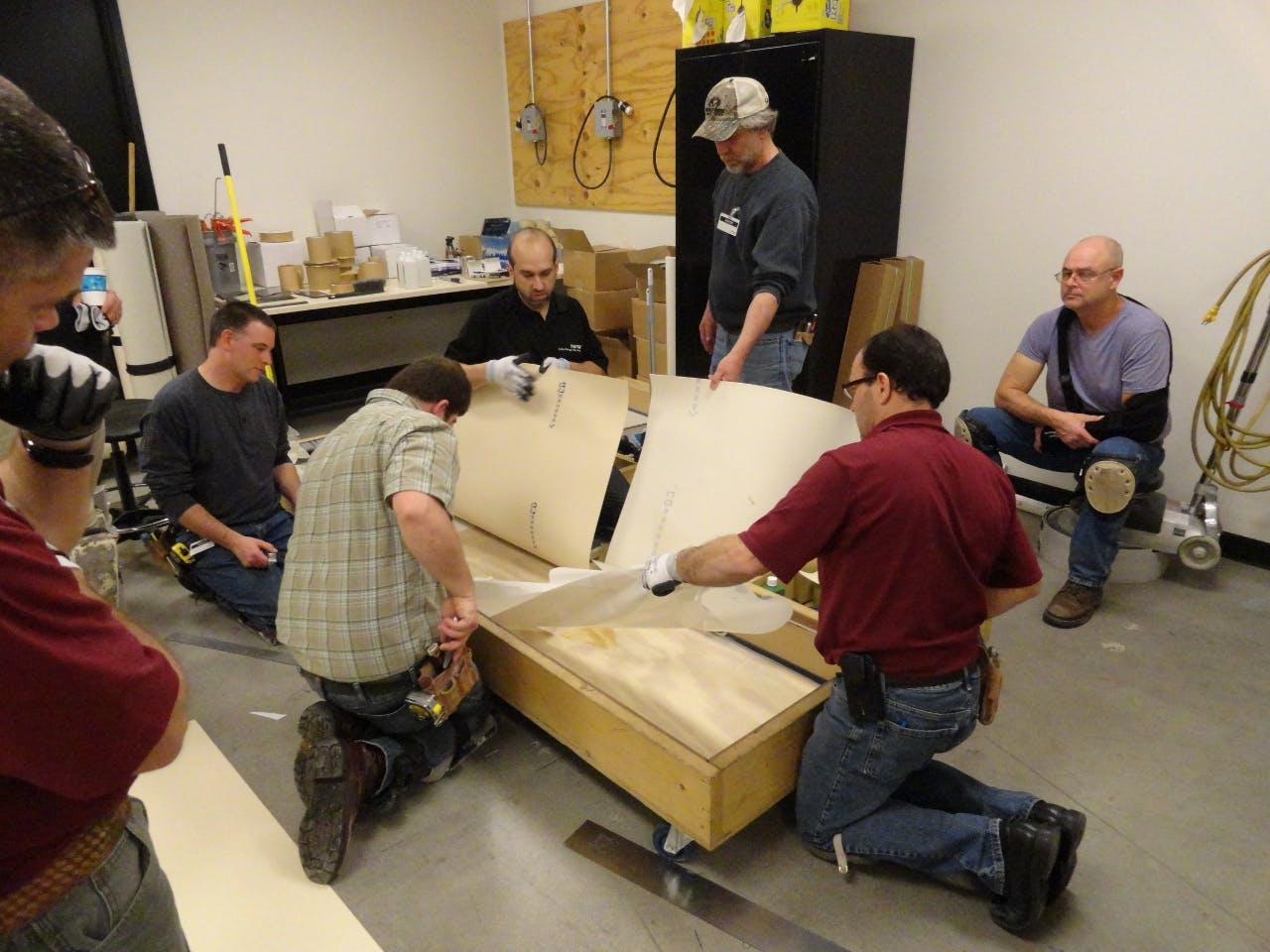 Technical Academy instructor Marc Ilgenfritz, center facing, invites installers to remove the backing from nora dryfix adhesive