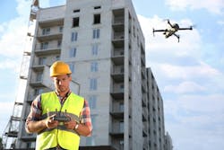 Builder operating drone with remote control at construction site. Aerial photography Builder operating drone with remote control at construction site. Aerial photography