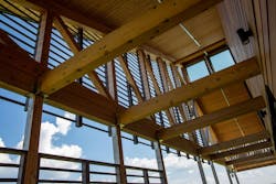 timber frame trusses sitting beneath blue sky with white clouds timber frame trusses sitting beneath blue sky with white clouds