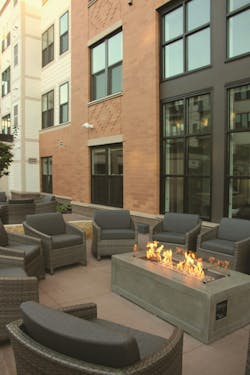 A modern apartment exterior with comfortable seating around a fire pitand no visible HVAC units to get in the way A modern apartment exterior with comfortable seating around a fire pitand no visible HVAC units to get in the way