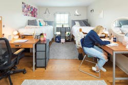Interior dorm room with woman at desk Interior dorm room with woman at desk