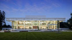 Evening view of a two story academic building light up from within shining out through full glass windows Evening view of a two story academic building light up from within shining out through full glass windows