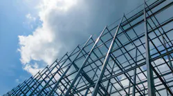 A large building of steel structure in the sky with sun and clouds.
