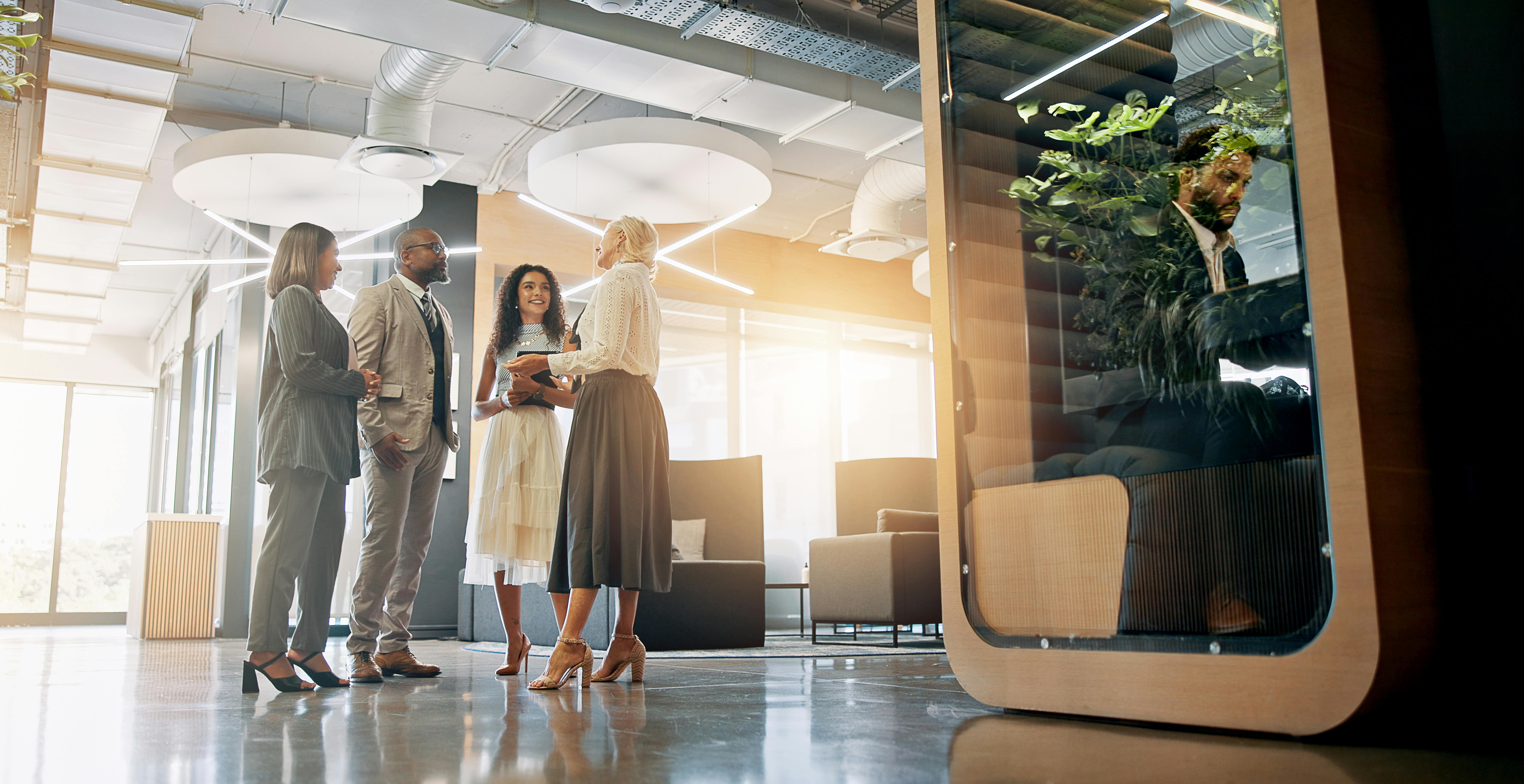 Lobby, talking and business people in office for coworking space for collaboration, teamwork and discussion. Professional, corporate and men and women in meeting with cubicle for private workspace.