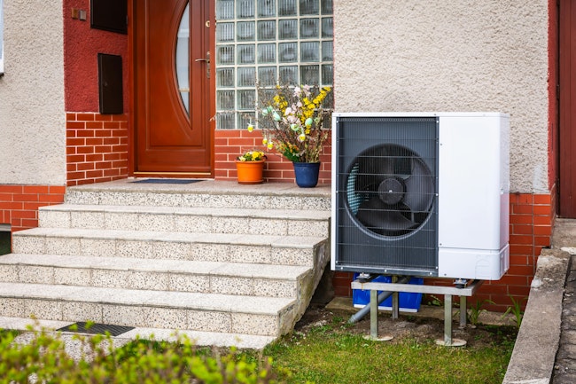 Air source heat pump installed outside of old renovated house, green renewable energy concept of heat pump.