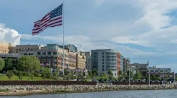 USA Flag flying at National Harbor in Maryland near Washington DC. National Harbor, MD - 24 June 2023: Skyline of National Harbor with large USA Flag flying near Washington DC