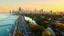 Chicago Cityscape at Sunset with Lakefront View. Aerial view of Chicago skyline at sunset, showing Lake Michigan shoreline, tree-lined parks, and a busy roadway along the waterfront Chicago Cityscape at Sunset with Lakefront View. Aerial view of Chicago skyline at sunset, showing Lake Michigan shoreline, tree-lined parks, and a busy roadway along the waterfront