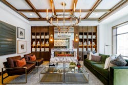 A stone fireplace anchors the resident club room at 619 North, where layered textures, warm wood tones and greenery create an inviting retreat A stone fireplace anchors the resident club room at 619 North, where layered textures, warm wood tones and greenery create an inviting retreat