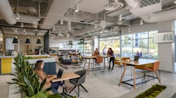 Mixed seating with tables in room with floor to ceiling windows with open garage style door, right. Coffee counter to left Mixed seating with tables in room with floor to ceiling windows with open garage style door, right. Coffee counter to left