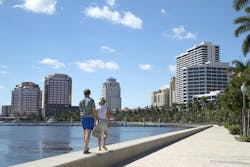 Couple enjoying the waterfront in West Palm Beach, Florida, USA. WEST PALM BEACH, FL, USA - October 3, 2015: Couple walks on the seawall at the West Palm Beach waterfront on a beautiful fall day. Couple enjoying the waterfront in West Palm Beach, Florida, USA. WEST PALM BEACH, FL, USA - October 3, 2015: Couple walks on the seawall at the West Palm Beach waterfront on a beautiful fall day.