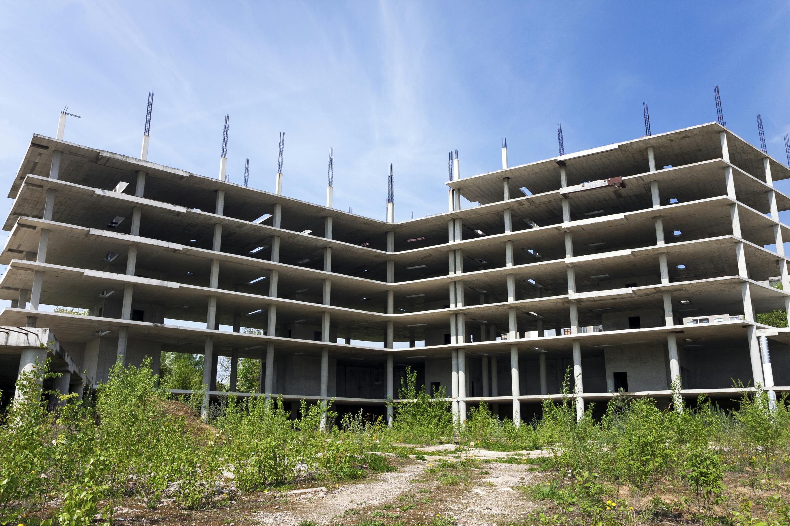 Abandoned construction site overgrown with grass on sunny summer day