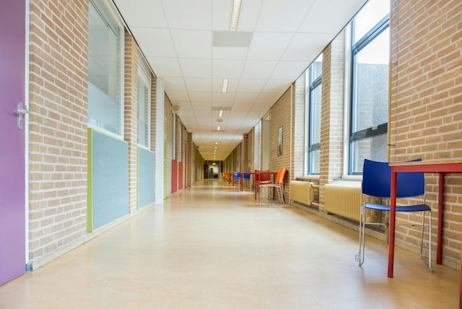 Long corridor with furniture in school building.