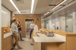 The cafe area is a destination for socialization within The Hub, part of amenities that include free snacks and beverages, showers, a lactation room, treadmills, lounge seating, TV, and more. Photo courtesy CannonDesign The cafe area is a destination for socialization within The Hub, part of amenities that include free snacks and beverages, showers, a lactation room, treadmills, lounge seating, TV, and more. Photo courtesy CannonDesign