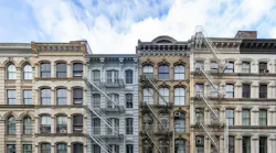 Exterior view of old apartment buildings in the SoHo neighborhood of Manhattan in New York City with empty blue sky background overhead
