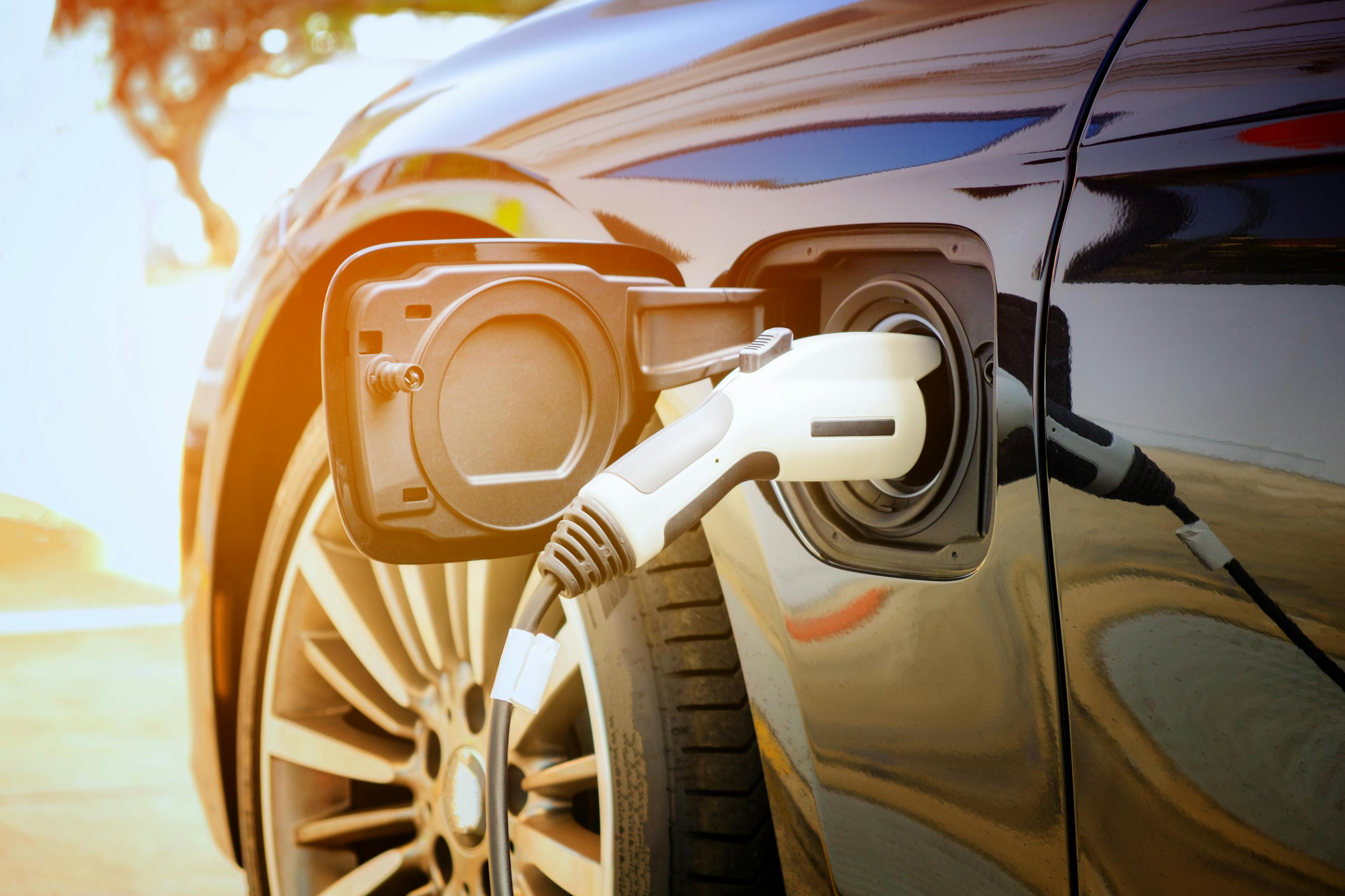 Charging modern electric car battery on the street which are the future of the Automobile, Close up of power supply plugged into an electric car being charged for hybrid. New era of vehicle fuel.