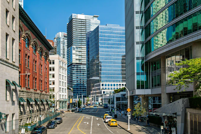View of Cordova Street in downtown Vancouver during summer with buildings and vehicles. Vancouver, BC, Canada &ndash; July 19, 2026: Cordova Street in downtown Vancouver on a summer day. Tall buildings frame the street while cars and taxis are parked along the sides. The sky is clear and blue, adding a bright backdrop to the urban view. People can be seen walking along the sidewalks as they enjoy the warm weather