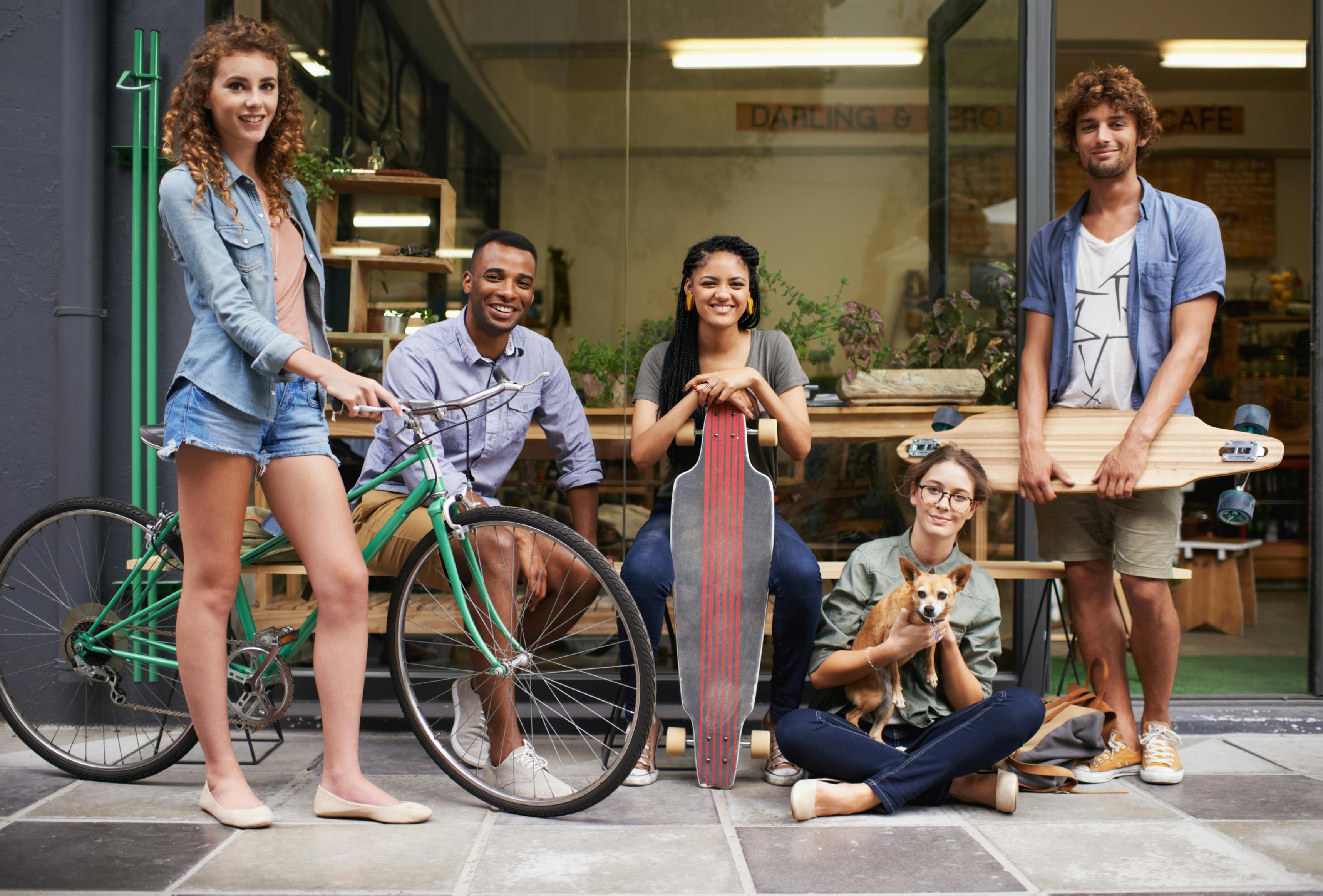 Bike, skateboard and portrait of urban friends on sidewalk together with smile, diversity and bonding. City, gen z style and group of people with street fashion, positive attitude and happy culture